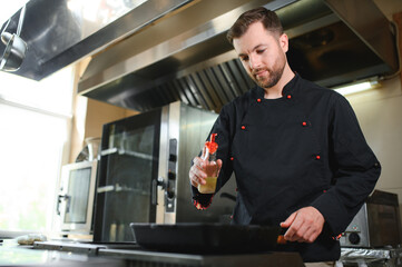 Portrait of happy caucasian male chef standing in restaurant kitchen, copy space