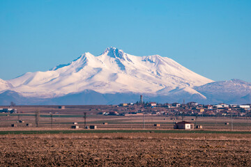 Snow-covered majestic mountain with a village at its base. Stunning winter scenery with a mountain and village. Selective focus.