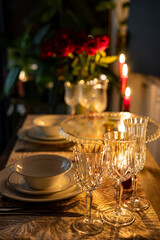 Romantic dinner for two on Valentine's Day. Wine glasses, roses bouquet and burning candles. Surprise dinner