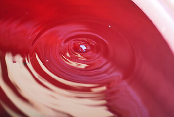 Close-Up of Red Liquid Surface with Concentric Ripples and Droplet