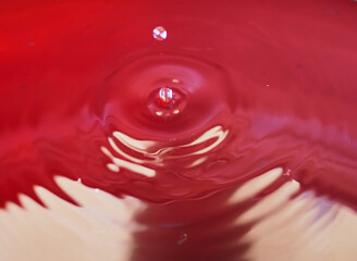 Close-Up of Water Droplet Splashing on Vibrant Red Surface