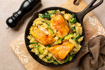 Top view of One pot baked Chicken Thighs and fusilli Pasta with zucchini and spinach.