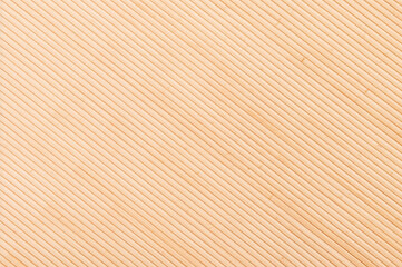 Fototapeta premium Diagonal light brown parallel lines form a bamboo texture.
