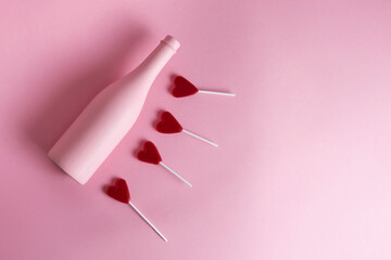 botella rosa en fondo rosa y paletas de corazon