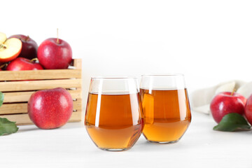 Fresh apple juice in glasses and fruits on white wooden table