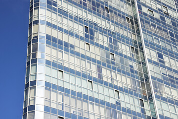 Fototapeta premium Exterior of modern building with many windows against blue sky, low angle view