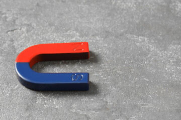One horseshoe magnet on grey textured table, closeup. Space for text