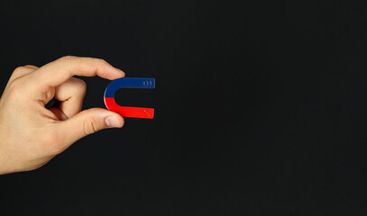 Man with horseshoe magnet on dark background, closeup. Space for text