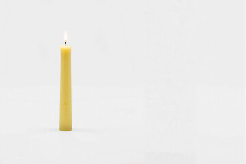 A tall yellow candle, standing upright, isolated on a white background, evoking calmness.