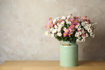 Beautiful flowers in modern vase on wooden table, space for text