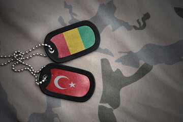 vintage army blank, dog tag with flag of guinea and turkey on the khaki texture background....