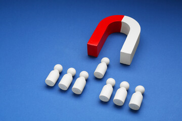Magnet attracting human figures on blue background