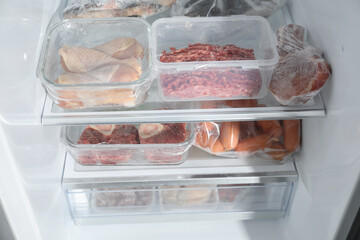 Different frozen meat products on shelves in fridge