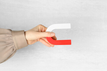 Woman with horseshoe magnet on light background, closeup