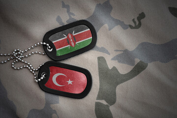 vintage army blank, dog tag with flag of kenya and turkey on the khaki texture background. military...