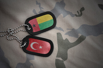vintage army blank, dog tag with flag of guinea bissau and turkey on the khaki texture background....