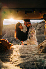 Couple embracing in camper van at sunset in desert landscape