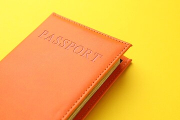 Passport in orange cover on yellow background, closeup