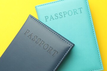 Passports in color covers on yellow background, top view