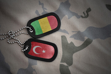 vintage army blank, dog tag with flag of mali and turkey on the khaki texture background. military...
