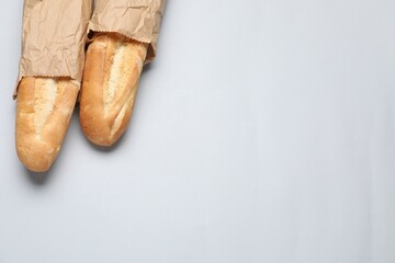 Paper bags with fresh baguettes on white background, top view. Space for text