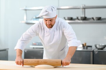 A male cook is mixing the dough in the kitchen. Production of various semi-finished products