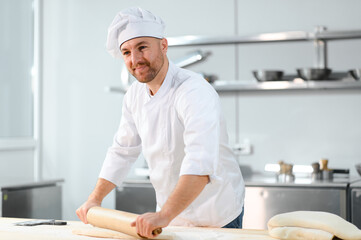 A male cook is mixing the dough in the kitchen. Production of various semi-finished products