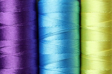 Spools of bright sewing threads as background, top view