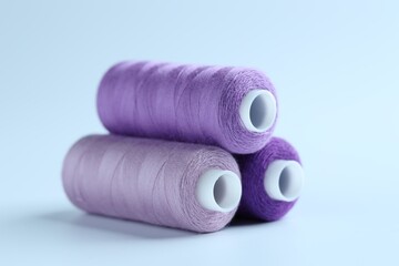 Spools of colorful sewing threads on light background, closeup