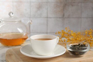 Refreshing green tea and dry leaves on white marble table, closeup