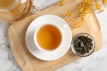 Refreshing green tea and dry leaves on white marble table, flat lay