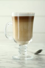 Tasty latte macchiato in glass cup on white marble table, closeup