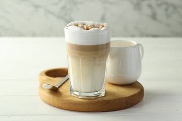 Tasty latte macchiato in glass on white wooden table, closeup