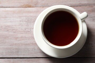 Refreshing black tea in cup on light wooden table, top view. Space for text