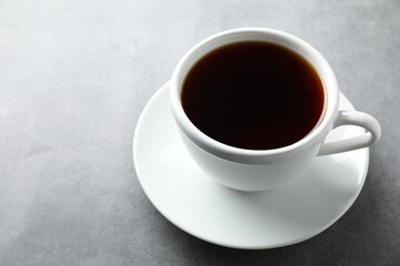 Refreshing black tea in cup on grey table, closeup. Space for text