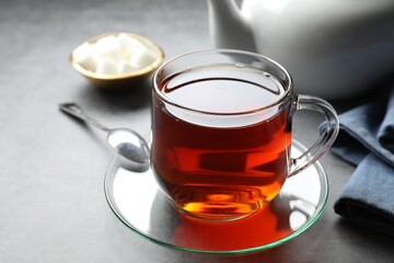 Refreshing black tea in cup on grey table, closeup