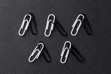 Many paper clips on black background, flat lay