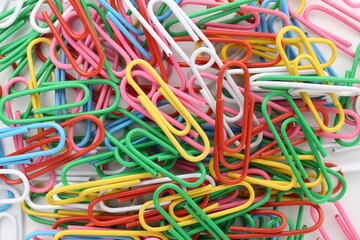 Colorful paper clips on light background, top view