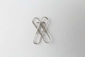 Metal paper clips on light background, top view