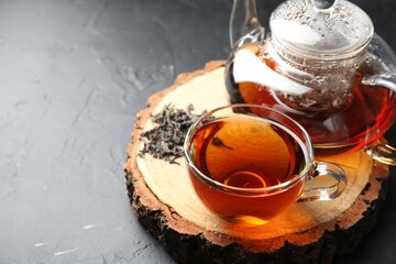 Aromatic black tea and dry leaves on grey table, closeup. Space for text