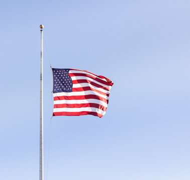 american flag at half mast against blue sky