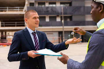 Commissioning of the new shopping center - businessman and builder exchange keys and documents