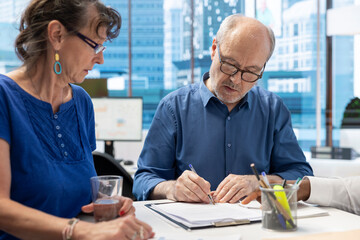 Elderly man signing the retirement plan contract with the broker, agreeing to life insurance policy...