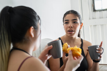 close-up of the face of a young latina woman talking to her friend while drinking coffee and eating...
