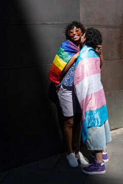 LGBTQ+ couple embracing with pride, wrapped in rainbow flags