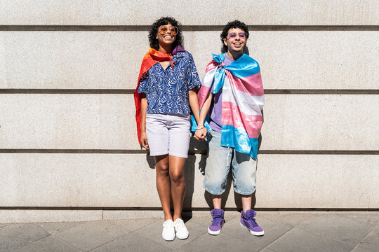 Multicultural LGBTQ+ couple celebrates pride with flags under the sun