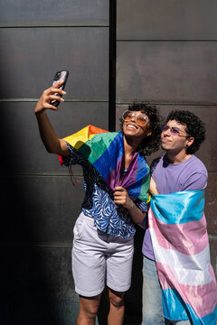 Happy LGBTQ+ couple taking a selfie with pride flags