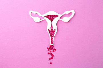 Menstruation. Paper uterus with sequins on violet background, top view