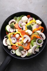 Frying pan with mix of vegetables and mushrooms on grey table, top view