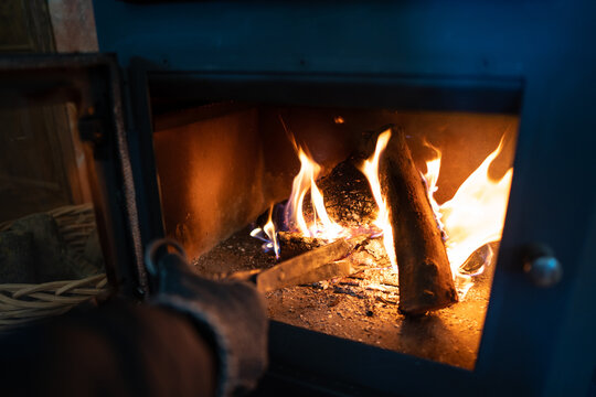 Cozy fire in a wood burning stove with hand stoking wood